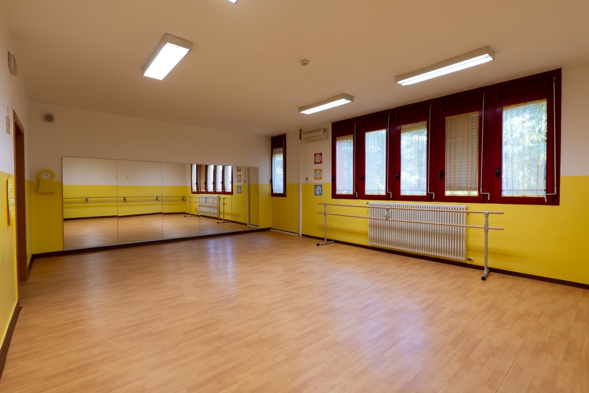 Sala danza con parquet, specchi e pareti gialle